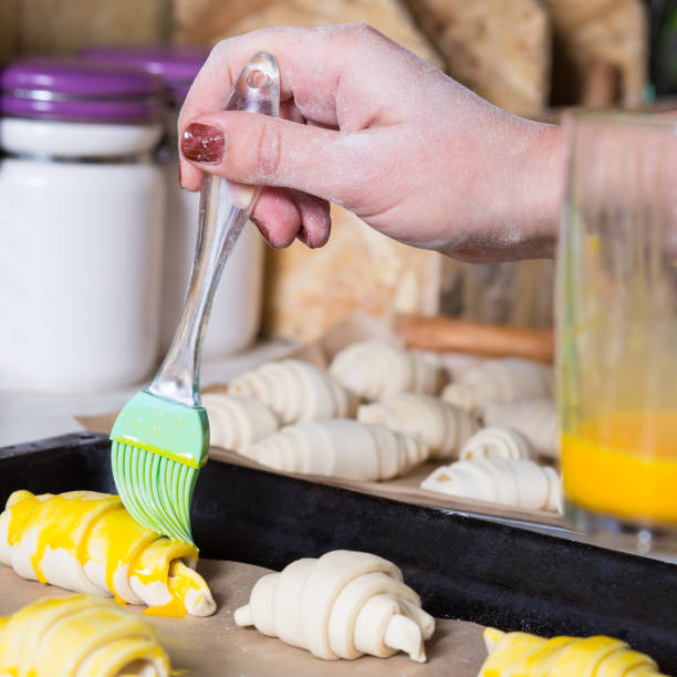 istock Brushing croissants on tray. Making croissatnts at home 1301758888