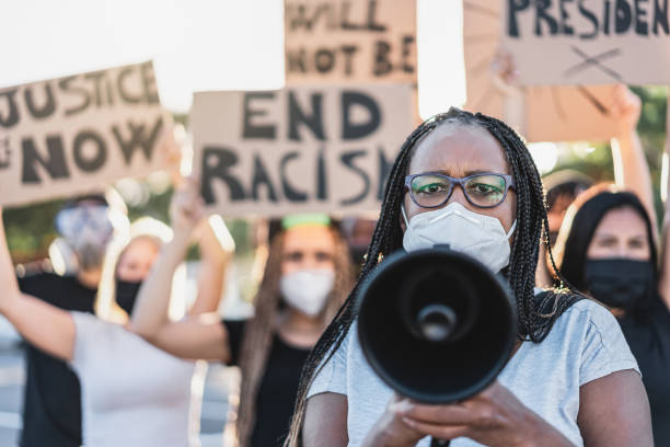 grupo de manifestantes en la carretera de diferentes culturas protestan por la igualdad de derechos - centrarse en la mujer mayor africana - antirracismo fotografías e imágenes de stock