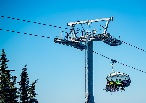 Hafjell, Norway - Feb. 6th 2021: Group of skiers riding a ski lift to the top of a mountain at a ski resort.