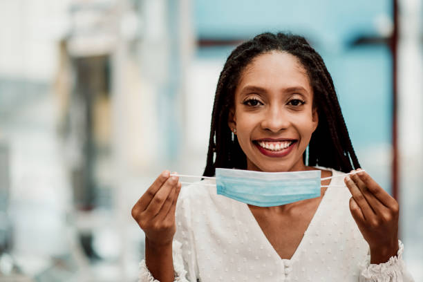 istock Woman smiling and removing face protection mask 1301764229