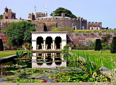 Queen Mother's Garden Walmer Castle Kent. Looking over a lily pond to an ornate refuge. green lawns to the sides and castle in the background. Restful and scenic.