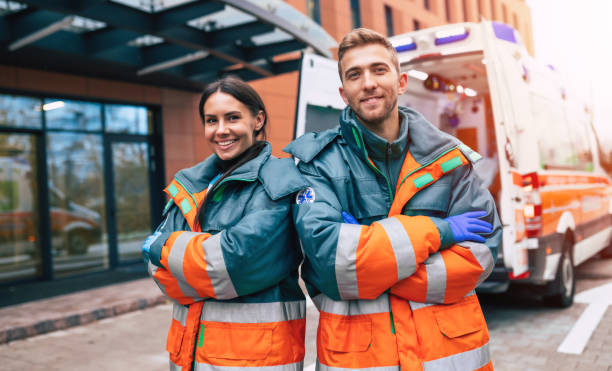 Two confident young doctors looking on the camera on ambulance and hospital background Two confident young doctors looking on the camera on ambulance and hospital background paramedic photos stock pictures, royalty-free photos & images
