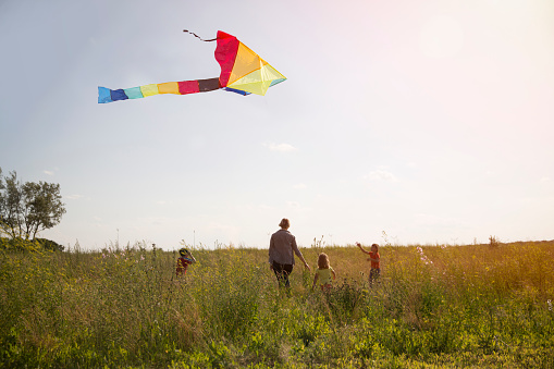 Family mom and kids with a kite in the field at sunset on a summer day