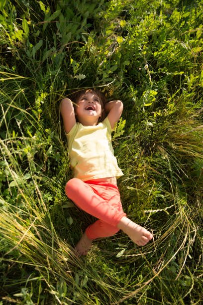 happy child lying on green grass outdoors in summer