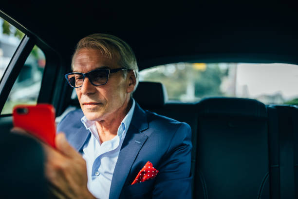 istock Businessman in taxi using smartphone 1301771707
