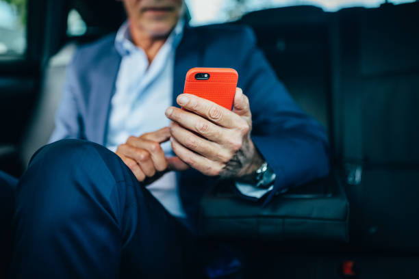 istock Businessman in taxi using smartphone 1301771763