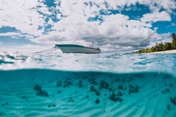 istock Tropical transparent ocean with white boat in Mauritius. Split view. 1301772368
