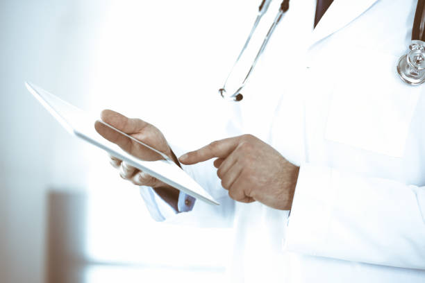 istock Doctor man using tablet computer for network research or virtual disease treatment, hands close-up. Perfect medical service in clinic. Modern medicine, medic data and healthcare concepts. Toned picture 1301772710