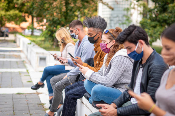 istock redhead woman student using smart phone covered by face mask during covid19 second wave, new normal lifestyle concept with millennials people looking news on mobile cellphone, selective focus 1301774192