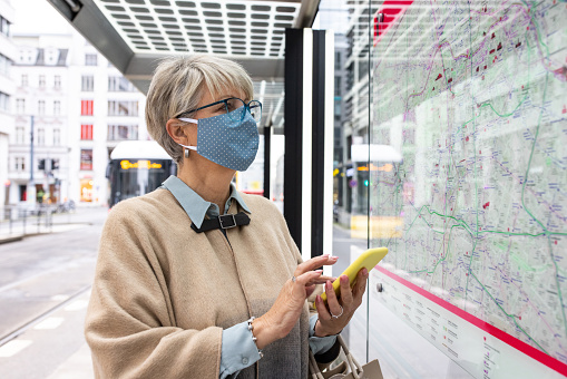 Female masked commuter looking at the bus line on map