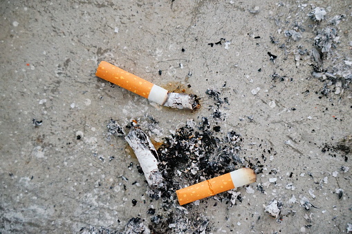 Cigarette butts are strewn on the ground
