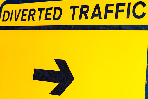 Close-up of an arrow on a yellow diverted traffic road sign, during road construction works.