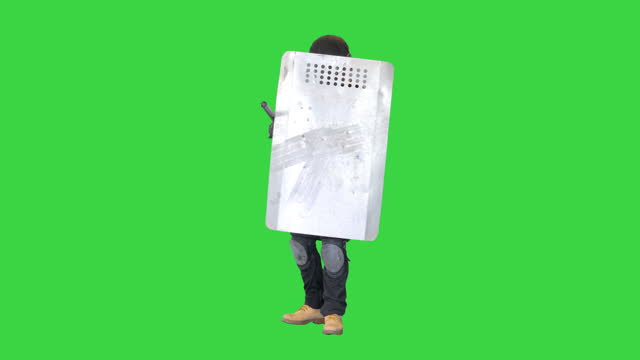 Soldier in full uniform covering with protective shield moving forward on a Green Screen, Chroma Key