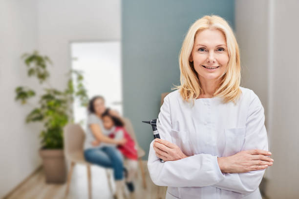 Female audiologist with otoscope in hands standing over background her patients in a hearing clinic Female audiologist with otoscope in hands standing over background her patients in a hearing clinic audiologist stock pictures, royalty-free photos & images