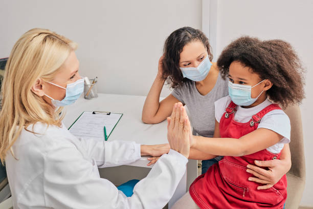 enfant afro-américain avec sa mère utilisant des masques protecteurs à la consultation générale de praticien. pandémie mondiale - primary care photos et images de collection