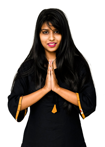 Afro American young woman praying and holding hands in prayer gesture standing isolated on dark beige studio background with copy space, smiling with eyes closed, Praying and hope concept