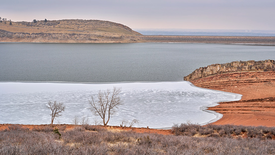 winter scenery of mountain lake at foothills of Rocky Mountains, partially frozen Horsetooth Reservoir - a popular recreational area in northern Colorado