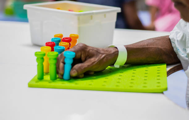 terapia ocupacional: entrenamiento de la función de la mano en el paciente con accidente cerebrovascular mediante el uso de varios colores pegboard. - occupational therapy fotografías e imágenes de stock