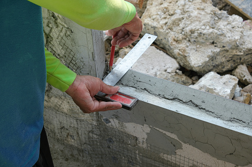 plaster worker use stainless steel ruler measure lightweight cement window brick prepare for install.