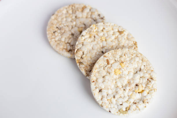 Close-up of two rice cakes with jam on a wooden cutting board over a yellow background.