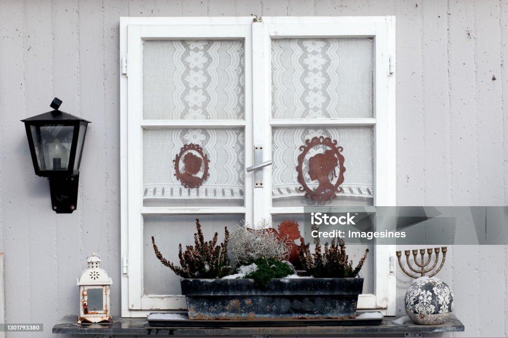 Traditional old window shutters with lantern and Autumn, winter flowers basket box decorations on the windowsill, concrete stone house Mediterranean style Autumn Stock Photo