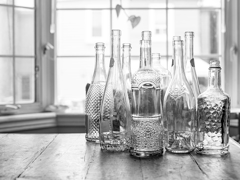 Vintage glass bottles on the kitchen table. Interior of private home in winter.