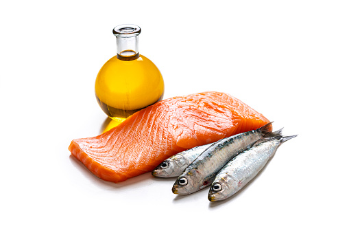 Healthy eating for well balanced diet and heart care: close up view of food with high content of healthy fats isolated on white background. A salmon steak, sardines and a bottle with extra virgin olive oil. High resolution 42Mp studio digital capture taken with Sony A7rII and Sony FE 90mm f2.8 macro G OSS lens