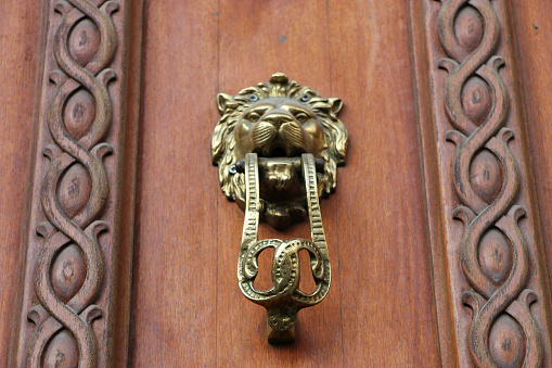 Old iron ring black knocker on vintage wooden retro brown door for knocking on facade classical europe house