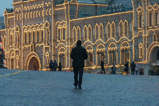 Moscow, Russia -  January 29, 2021. Handsome man walking in the Moscow city center during coronavirus pandemic. Festive Red Square. Brightly decorated building. GUM (Central department store)