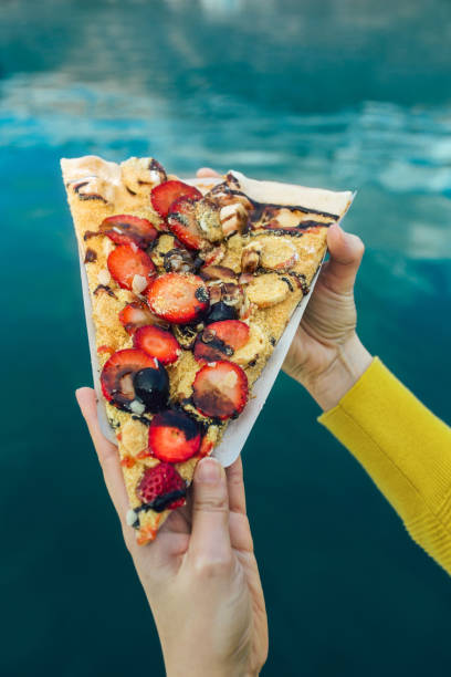istock Woman's hand holding italian pizza with fruit. 1301809616
