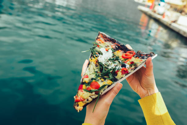 istock Woman's hand holding italian pizza with black dough and vegetables. 1301811280