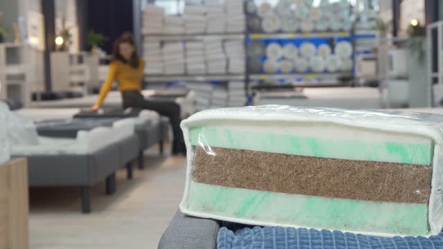 Unrecognizable woman shopping for new mattress at furniture store