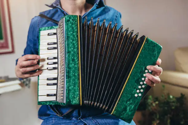 Close up detail of a girl playing the green accordion. Hands close-up