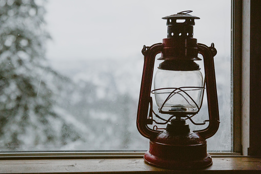 A gas lantern sits in a cold cabin window sill during winter in Winthrop, WA, United States