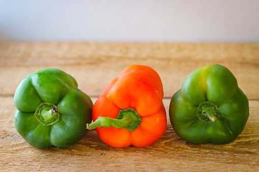 Red and green bell peppers on a wooden board