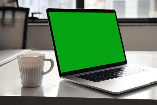 Mock-up Green Screen Laptop Standing on the Desk in the Office