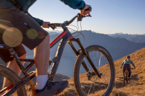 istock Mountain bikers ride down grassy mountain ridge at sunrise 1301827159
