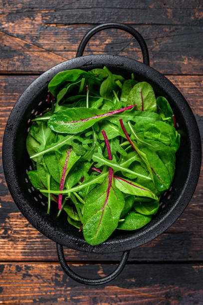 istock Fresh raw mixed greens, spinach, swiss chard and arugula. Dark wooden background. Top view 1301831792