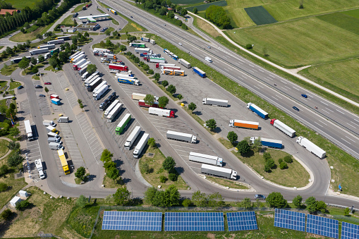 Heavy goods transportation - trucks in truck stop from above. Renewable energy plants are seen in the foreground.