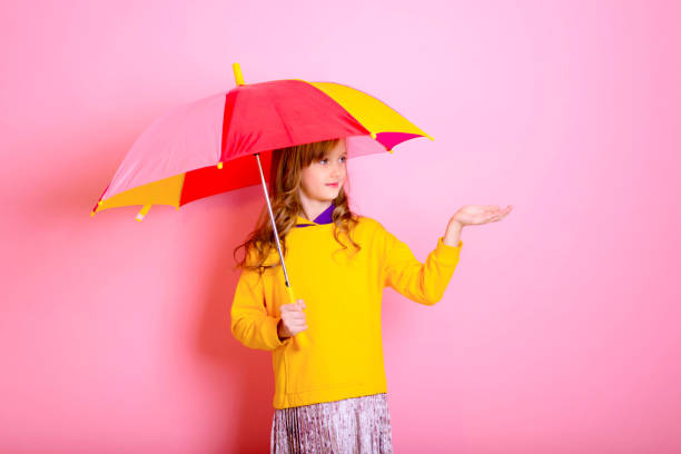 istock Girl is hiding under a colored umbrella on a pink background. 1301832808