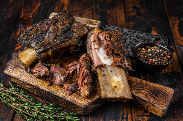 bbq kurze futter rind rippen mit kräutern und fleisch spalter. dunkle holzhintergrund. ansicht von oben - rippchen stock-fotos und bilder