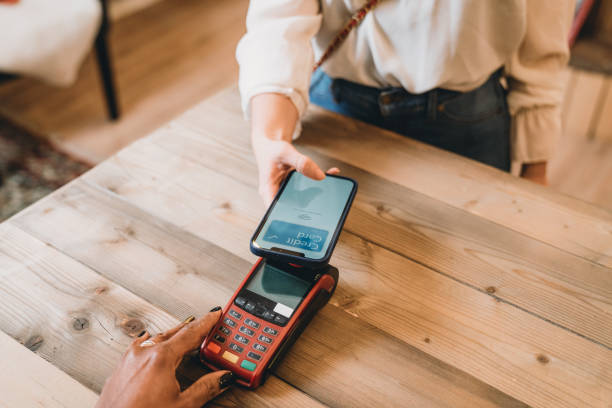 istock Young woman is paying using her phone with contactless technology in a shop 1301833139