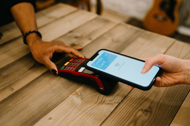 istock Young woman is paying using her phone with contactless technology in a shop 1301833151