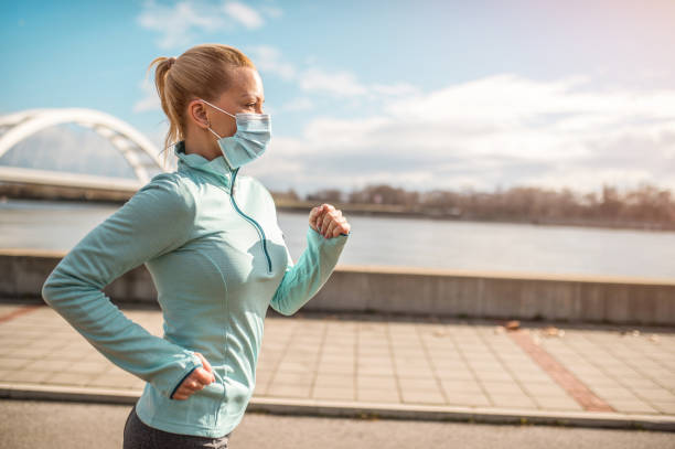 istock Young woman running with face mask on. 1301835420
