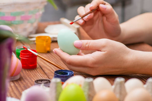 istock A woman with a tassel paints Easter eggs. Preparing decorations for Easter, creativity with children, traditional symbols. Preparing for Easter. 1301835591