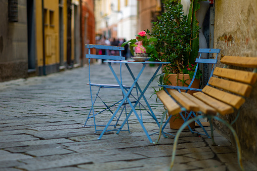 ¿where are our elderly people? 3 old blue wooden chairs alone in the mediterranean street on a white wall