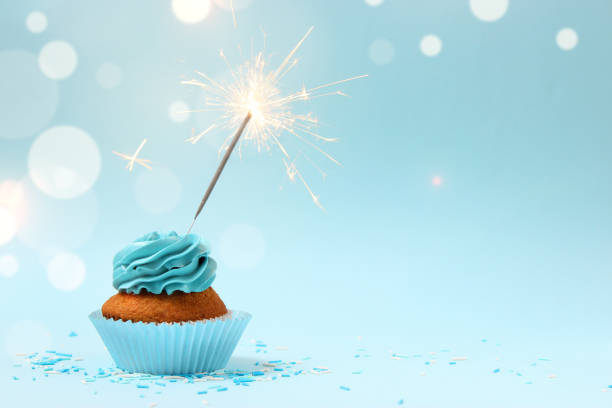 cupcake with cream and burning sparkler for a birthday or other holiday with a shopping plan on a colored background with bokeh lights - cupcake birthday birthday cake first place imagens e fotografias de stock