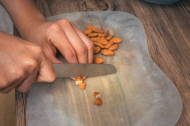 istock Person with kitchen knife cutting almonds 1301836467