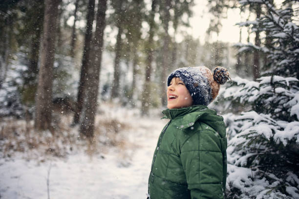 Kids hiking on winter day. Gust of wind is shaking a lot of snow on the happy little boy.\nShot with Canon R5