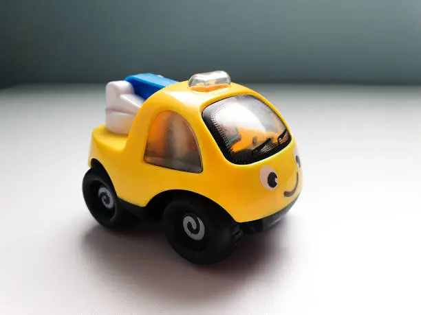 Colorful small car isolated on white background with shadow reflection. Plastic child toy on white backdrop. Plastic childrens toy. Kids plaything.